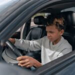 Een rijinstructeur geeft les aan een leerling in een auto, met focus op rijopleiding en kosten.